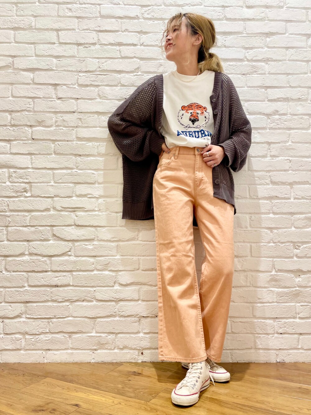 ホワイト系のTシャツ/カットソー、グレー系のカーディガン/ボレロ、オレンジ系のデニムパンツを着用したレディースの春コーディネートの2枚目の写真