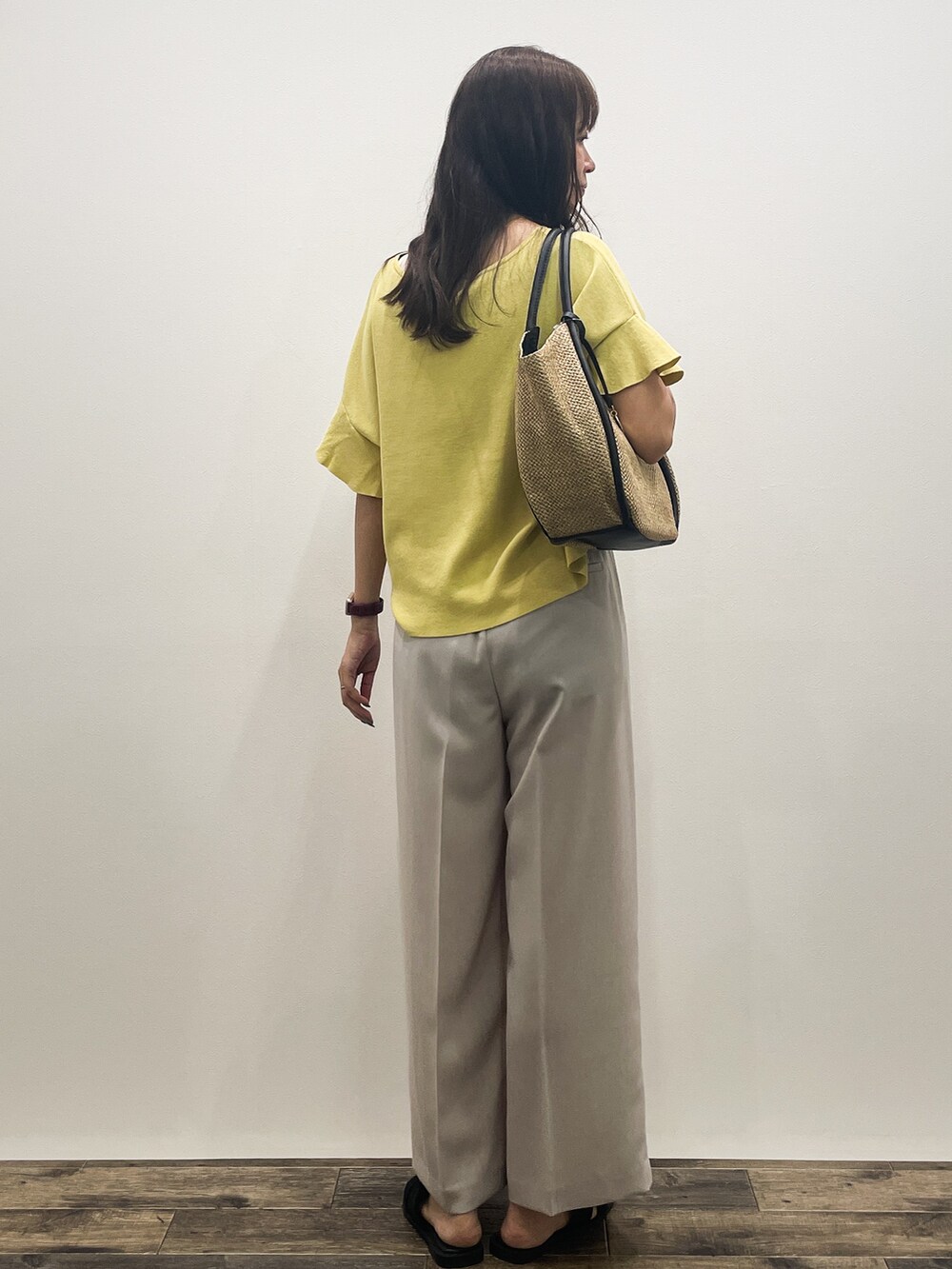 イエロー系のニット/セーター、ベージュ系のその他パンツ、ベージュ系のトートバッグを着用したレディースの春コーディネートの6枚目の写真
