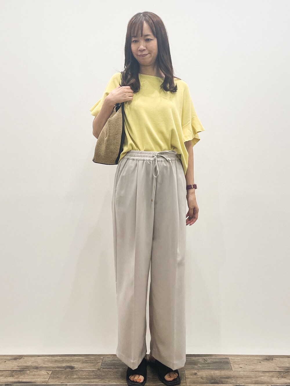 イエロー系のニット/セーター、ベージュ系のその他パンツ、ベージュ系のトートバッグを着用したレディースの春コーディネートの2枚目の写真