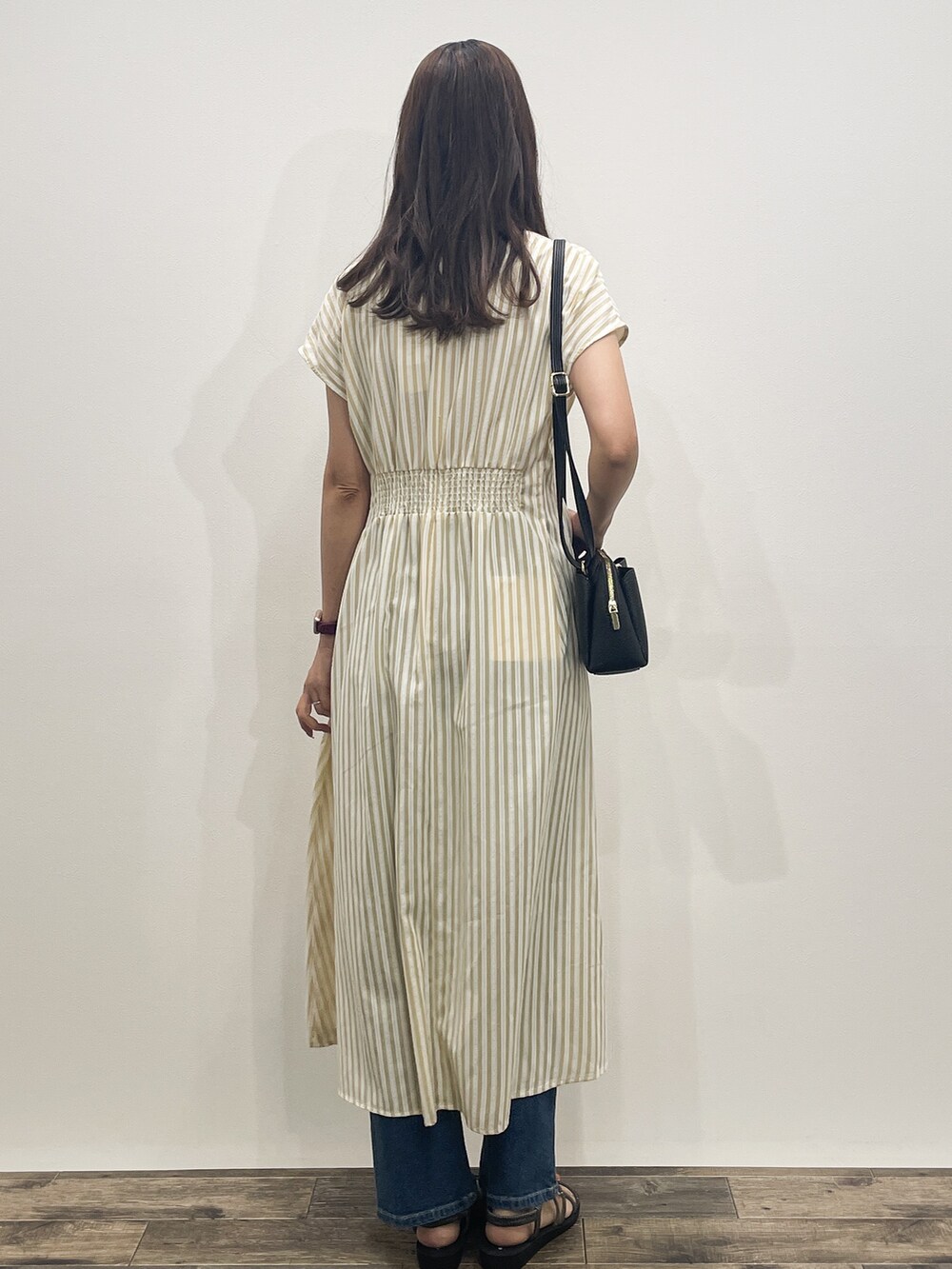 ベージュ系のワンピース、ブルー系のデニムパンツ、ブラック系のショルダーバッグを着用したレディースの夏コーディネートの5枚目の写真