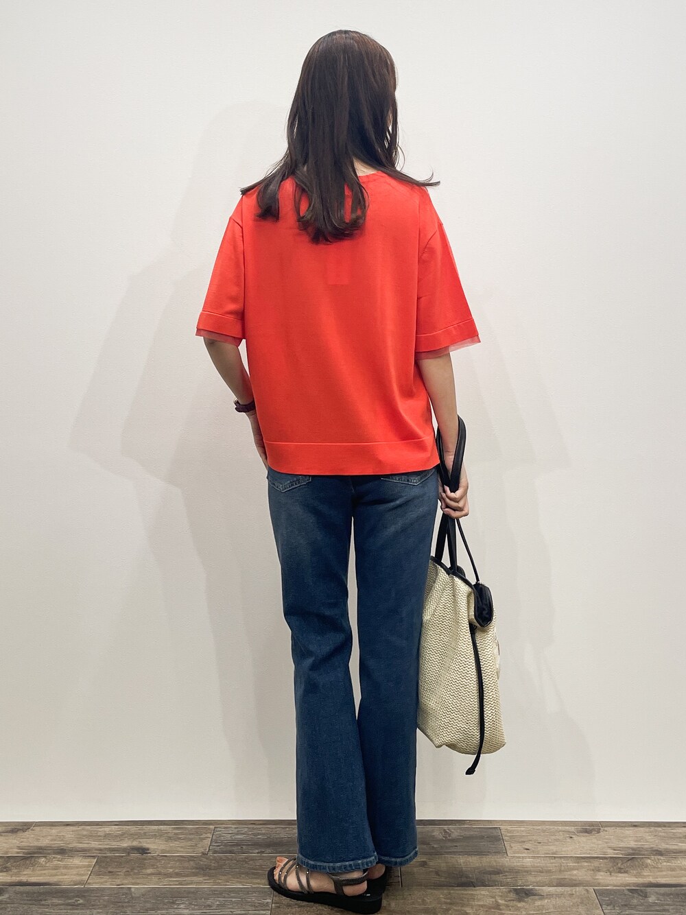 オレンジ系のニット/セーター、ブルー系のデニムパンツ、ホワイト系のトートバッグを着用したレディースの夏コーディネートの5枚目の写真