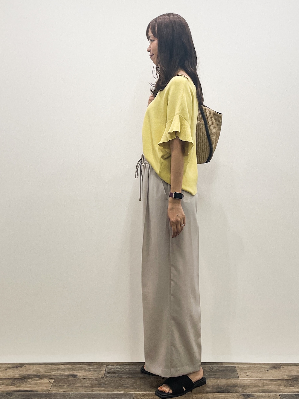 イエロー系のニット/セーター、ベージュ系のその他パンツ、ベージュ系のトートバッグを着用したレディースの春コーディネートの4枚目の写真