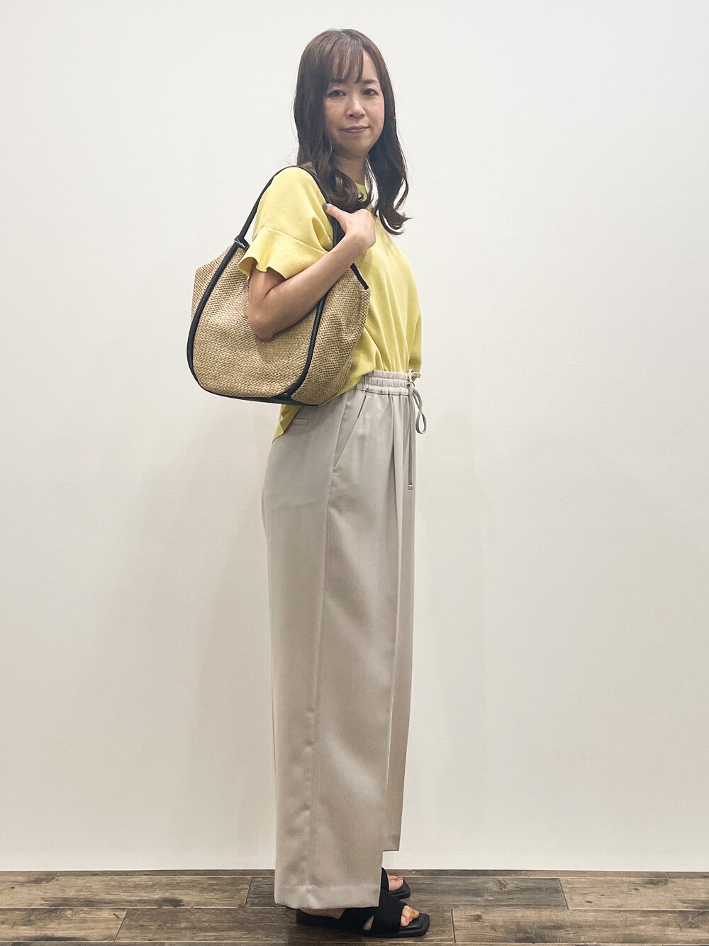 イエロー系のニット/セーター、ベージュ系のその他パンツ、ベージュ系のトートバッグを着用したレディースの春コーディネートの8枚目の写真