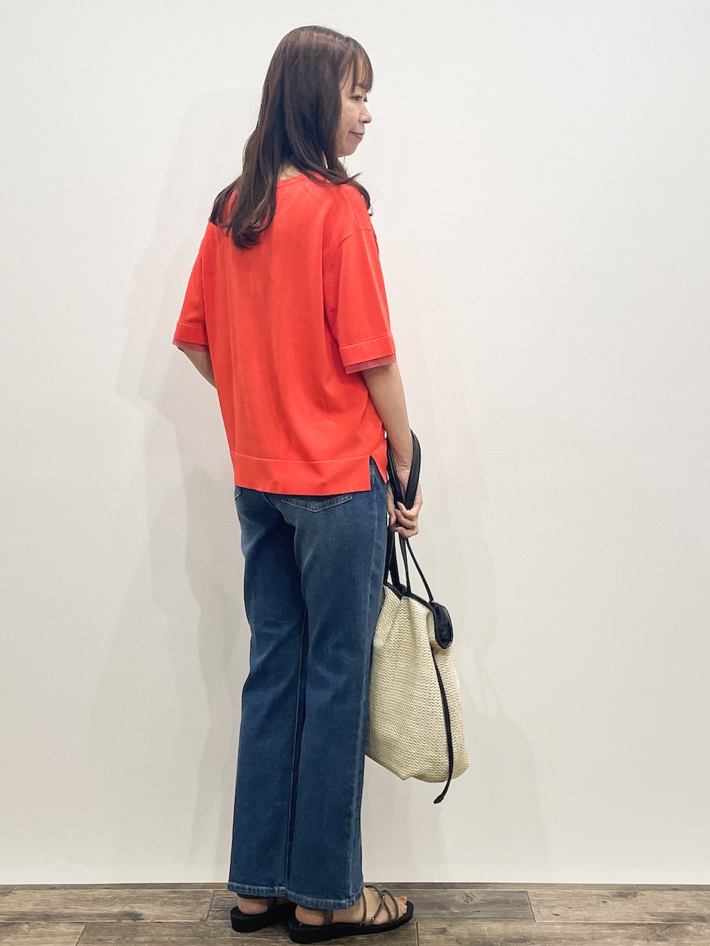 オレンジ系のニット/セーター、ブルー系のデニムパンツ、ホワイト系のトートバッグを着用したレディースの夏コーディネートの6枚目の写真