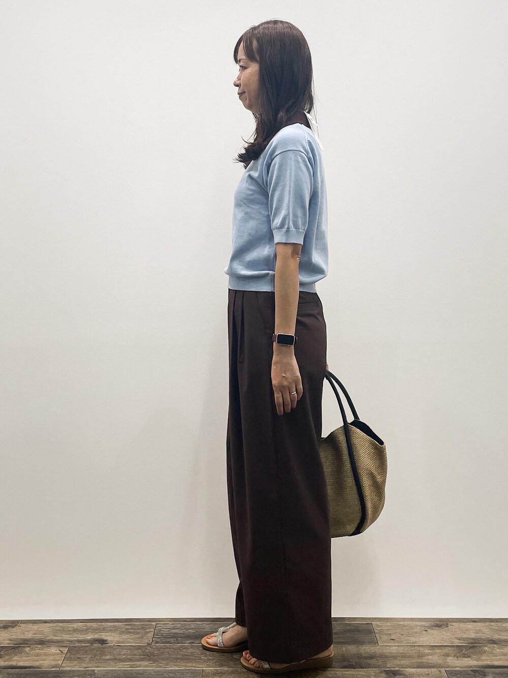 ブルー系のニット/セーター、ブラウン系のその他パンツ、ベージュ系のトートバッグを着用したレディースの春コーディネートの4枚目の写真