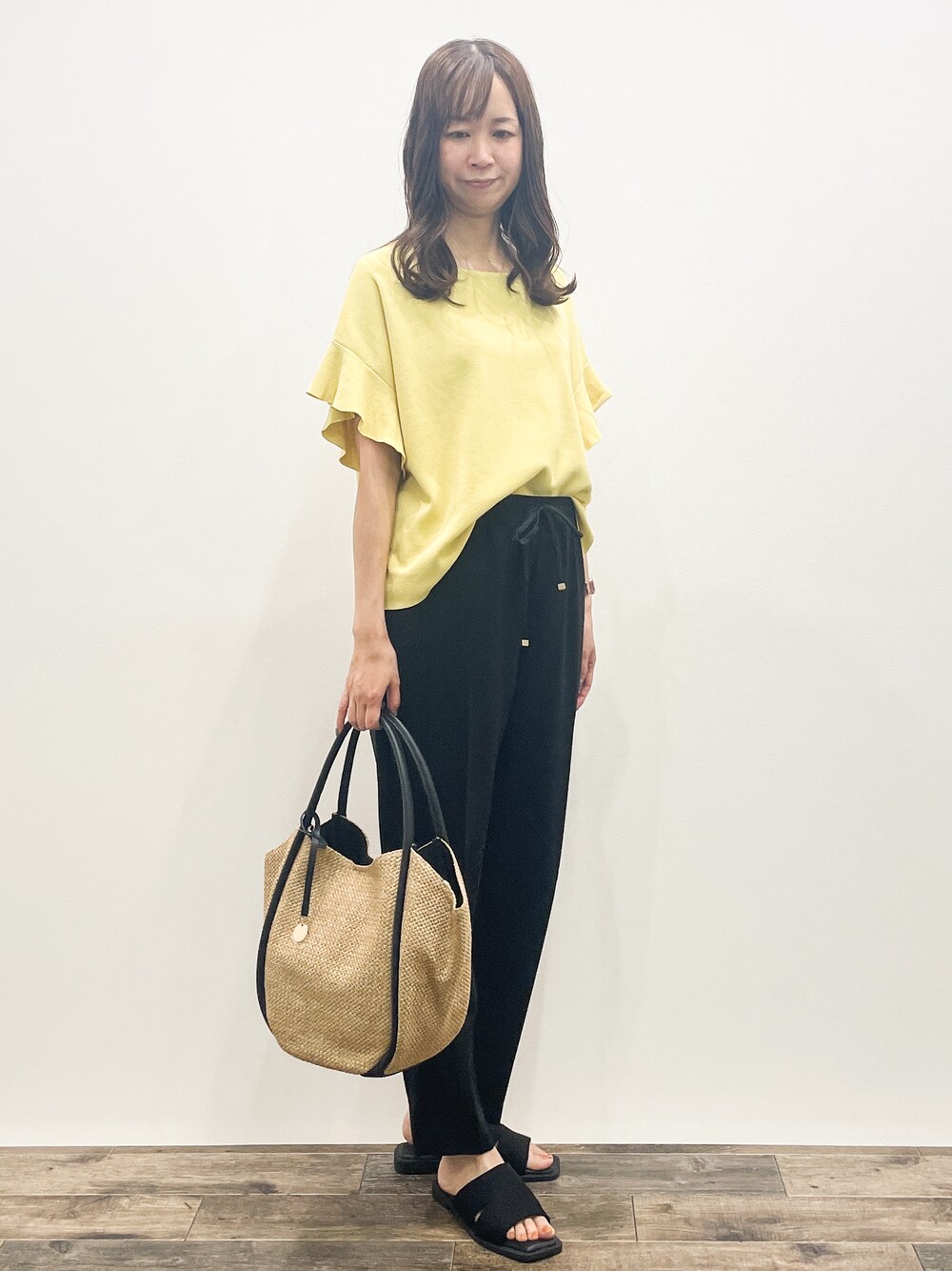 イエロー系のニット/セーター、ブラック系のその他パンツ、ベージュ系のトートバッグを着用したレディースの春コーディネートの8枚目の写真