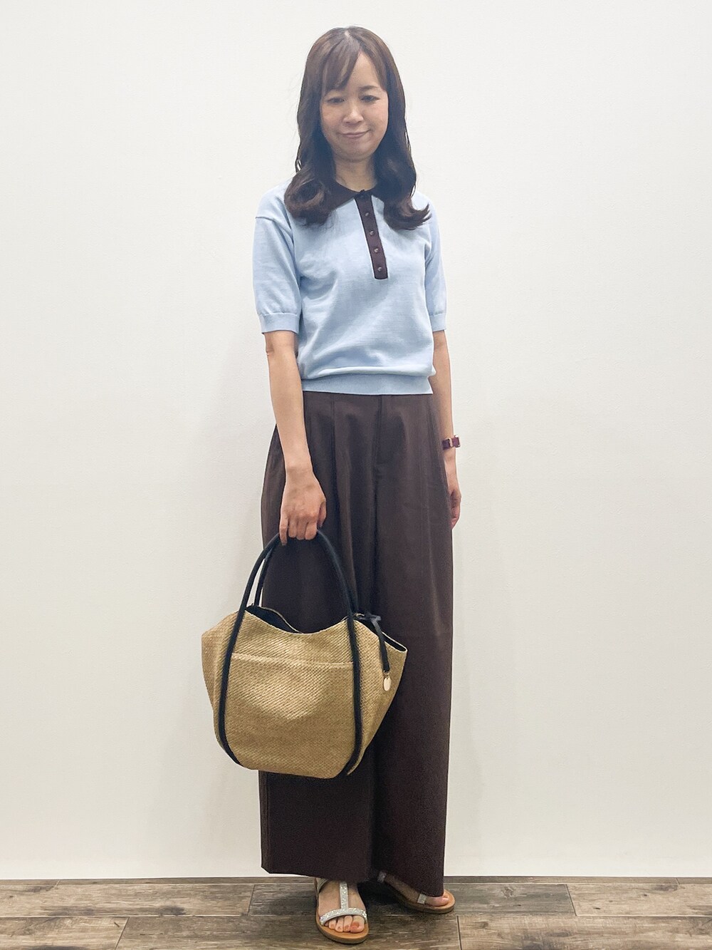 ブルー系のニット/セーター、ブラウン系のその他パンツ、ベージュ系のトートバッグを着用したレディースの春コーディネートの6枚目の写真
