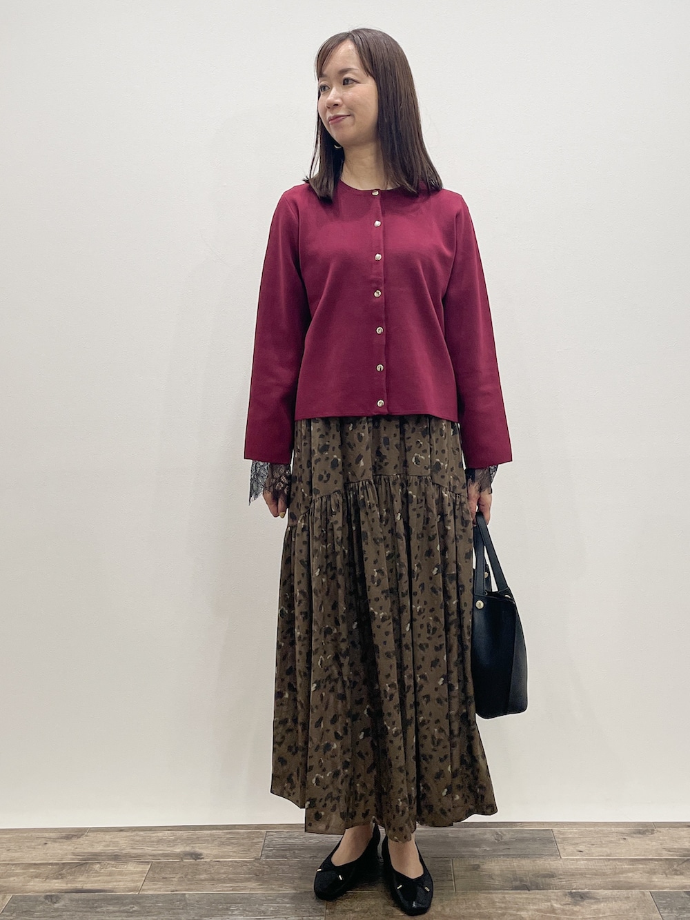 レッド系のカーディガン/ボレロ、グレー系のTシャツ/カットソー、ブラウン系のスカートを着用したレディースの秋コーディネートの2枚目の写真