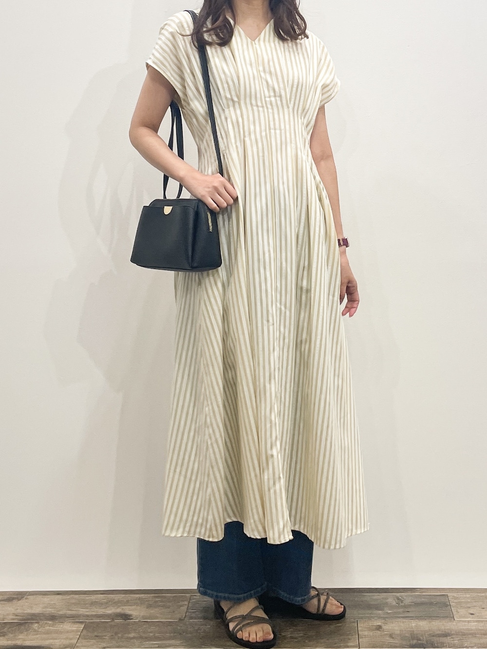 ベージュ系のワンピース、ブルー系のデニムパンツ、ブラック系のショルダーバッグを着用したレディースの夏コーディネートの8枚目の写真