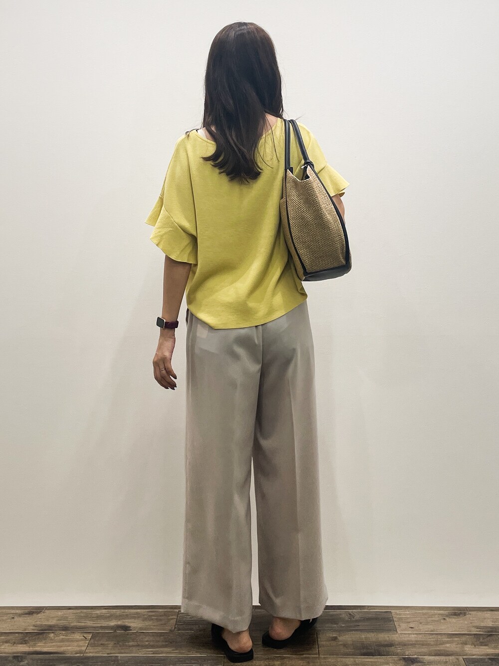 イエロー系のニット/セーター、ベージュ系のその他パンツ、ベージュ系のトートバッグを着用したレディースの春コーディネートの5枚目の写真
