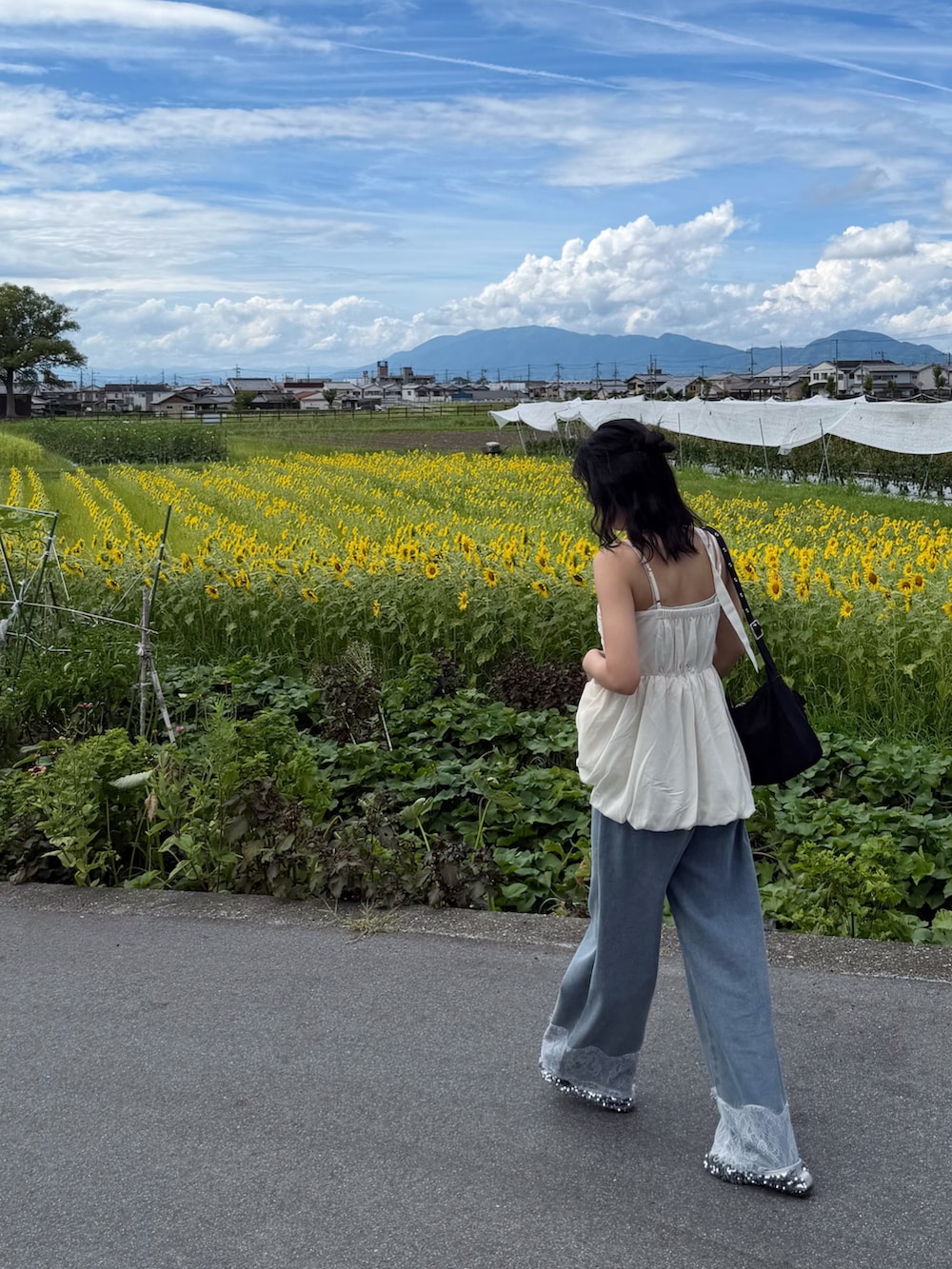 ベージュ系のチュニック、ブルー系のデニムパンツ、シルバー系のパンプスを着用したレディースの夏コーディネートの4枚目の写真