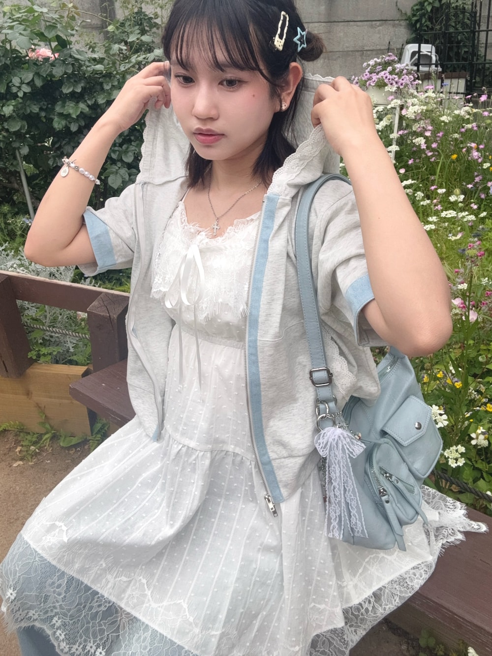 ホワイト系のチュニック、ベージュ系のパーカー、ブルー系のデニムパンツを着用したレディースの夏コーディネートの2枚目の写真
