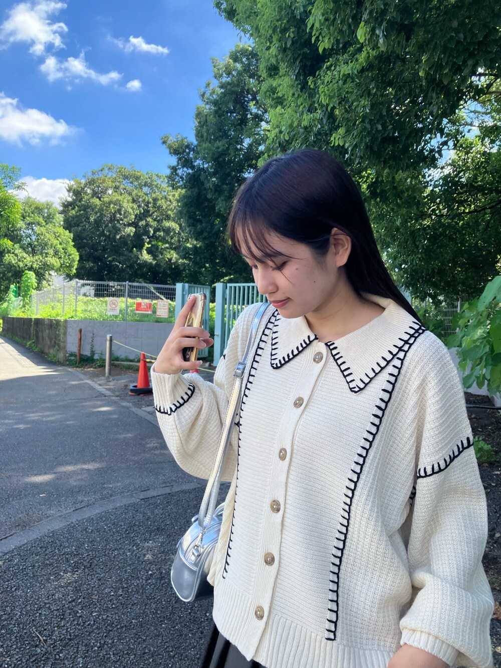 ブラック系のスカート、ブラック系のブーツ、ベージュ系のカーディガン/ボレロを着用したレディースの秋コーディネートの2枚目の写真