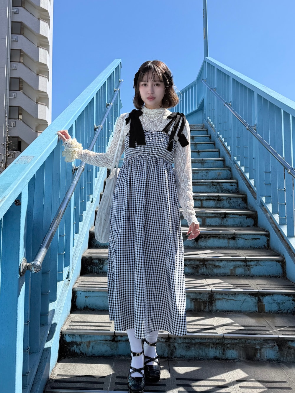 ブラック系のワンピース、ベージュ系のTシャツ/カットソー、ブラック系のパンプスを着用したレディースの春コーディネートの2枚目の写真