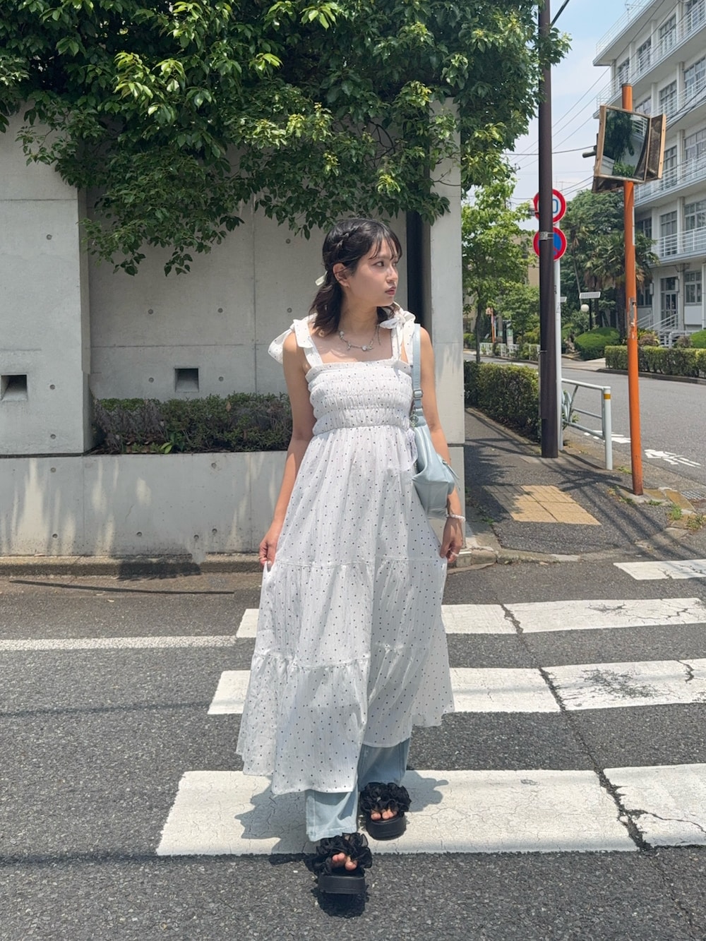 ホワイト系のワンピース、ブラック系のサンダル、ブルー系のデニムパンツを着用したレディースの夏コーディネートの2枚目の写真
