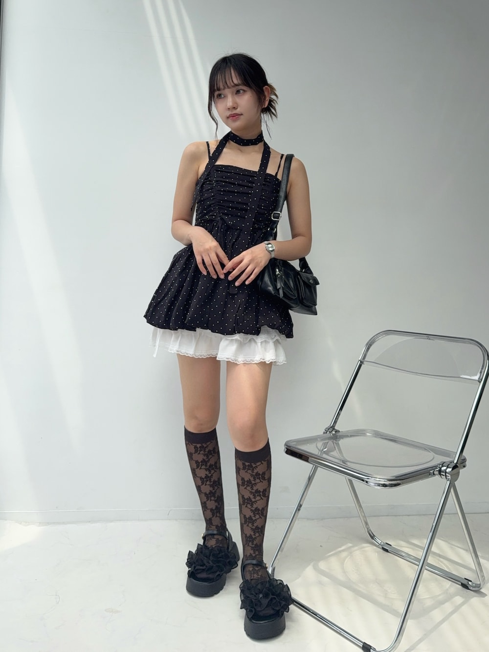 ブラック系のチュニック、ホワイト系のスカート、ブラック系のサンダルを着用したレディースの夏コーディネートの2枚目の写真