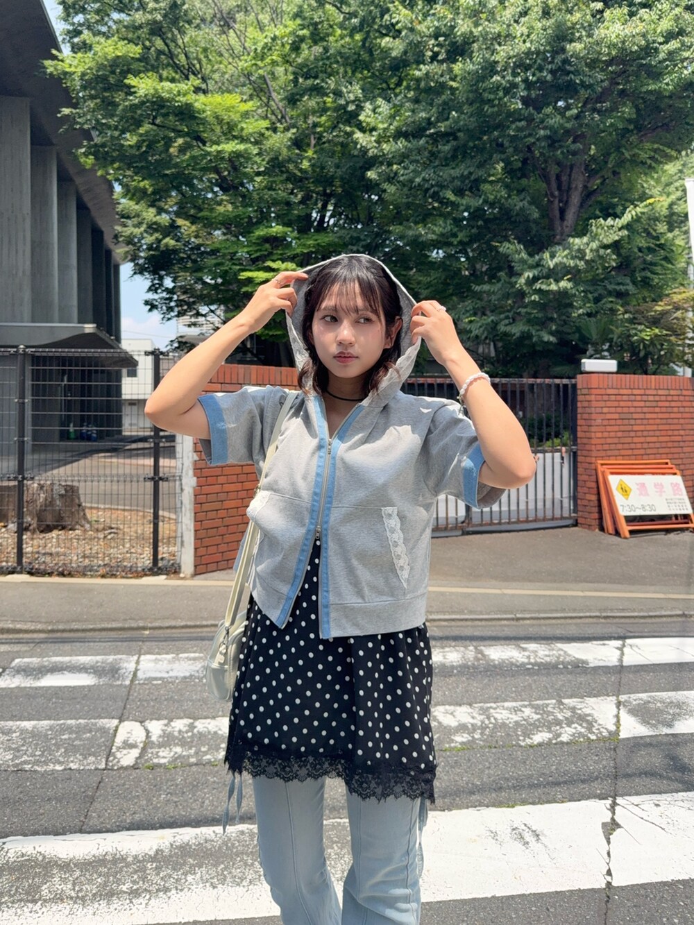 グレー系のパーカー、ブルー系のデニムパンツ、ブラック系のサンダルを着用したレディースの夏コーディネートの2枚目の写真