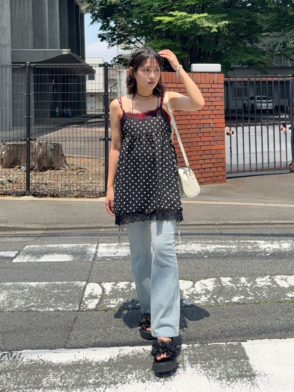 ブラック系のチュニック、ブルー系のデニムパンツ、レッド系のキャミソールを着用したレディースの夏コーディネートの2枚目の写真