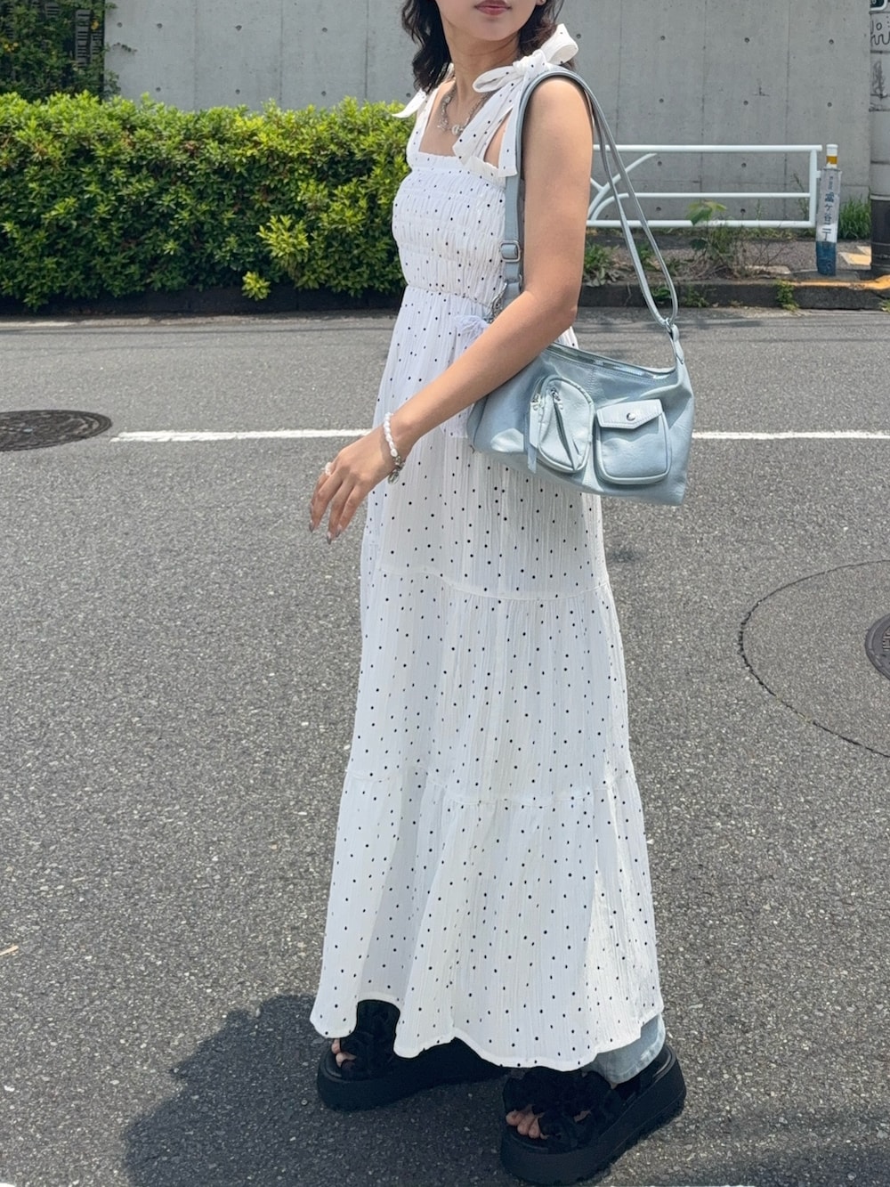 ホワイト系のワンピース、ブラック系のサンダル、ブルー系のデニムパンツを着用したレディースの夏コーディネートの3枚目の写真
