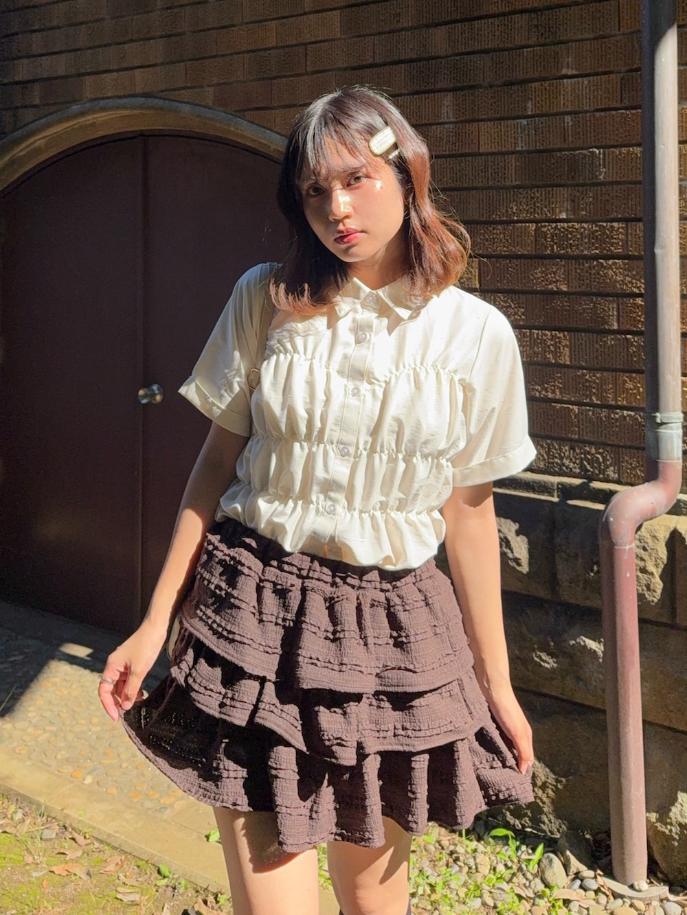 ブラウン系のスカート、ブラック系のサンダル、ベージュ系のシャツ/ブラウスを着用したレディースの夏コーディネートの4枚目の写真
