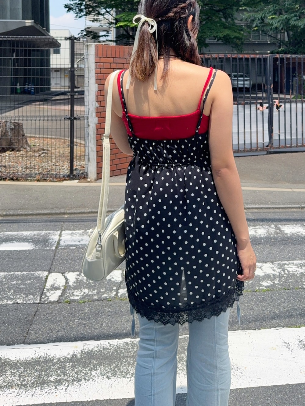 ブラック系のチュニック、ブルー系のデニムパンツ、レッド系のキャミソールを着用したレディースの夏コーディネートの5枚目の写真