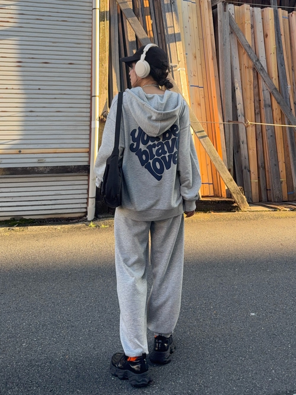 グレー系のパーカー、グレー系のスウェットパンツ、ブラック系のローファーを着用したレディースの夏コーディネートの2枚目の写真