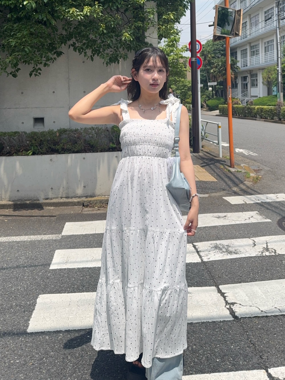ホワイト系のワンピース、ブラック系のサンダル、ブルー系のデニムパンツを着用したレディースの夏コーディネートの4枚目の写真