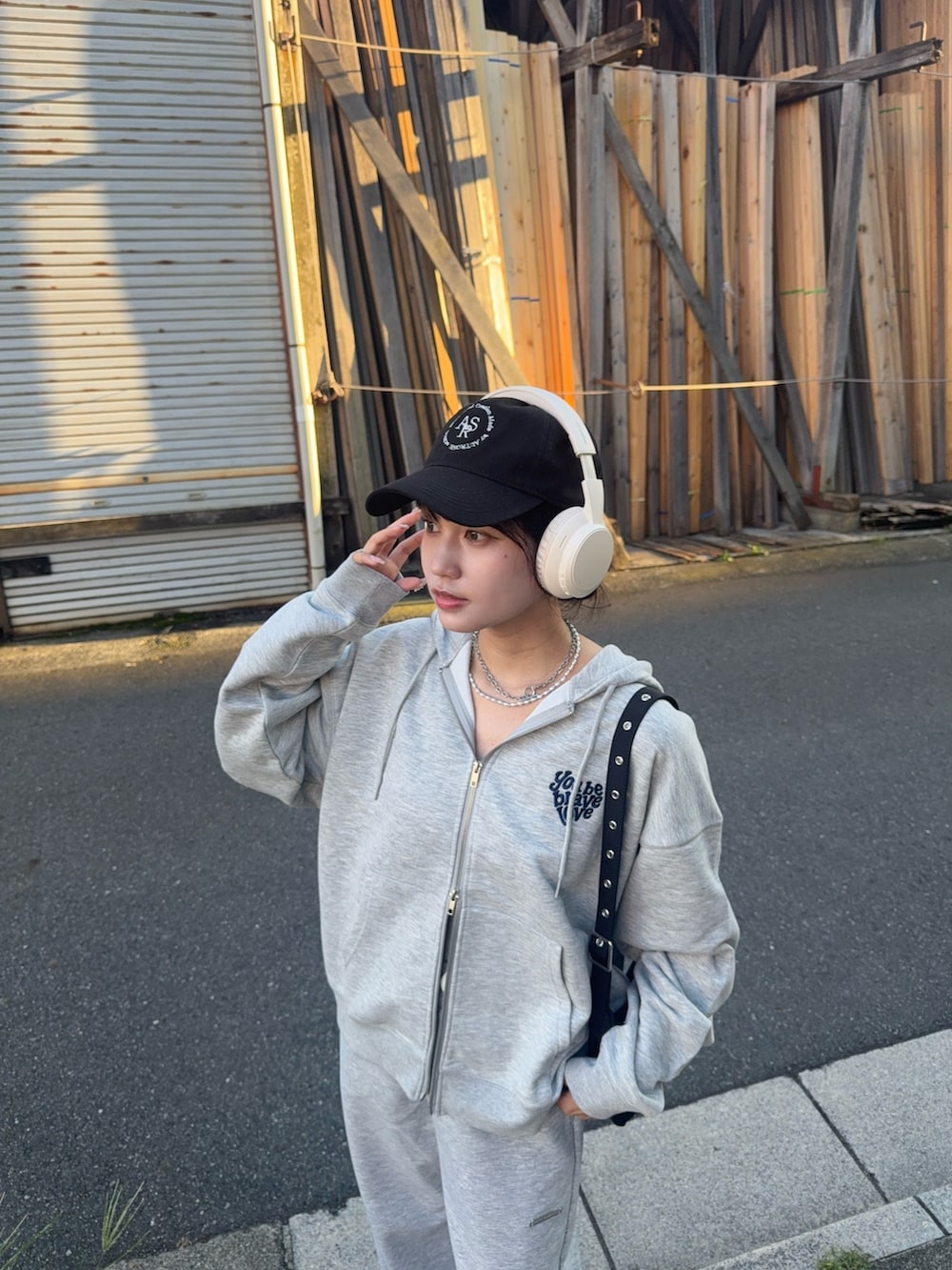 グレー系のパーカー、グレー系のスウェットパンツ、ブラック系のローファーを着用したレディースの夏コーディネートの5枚目の写真