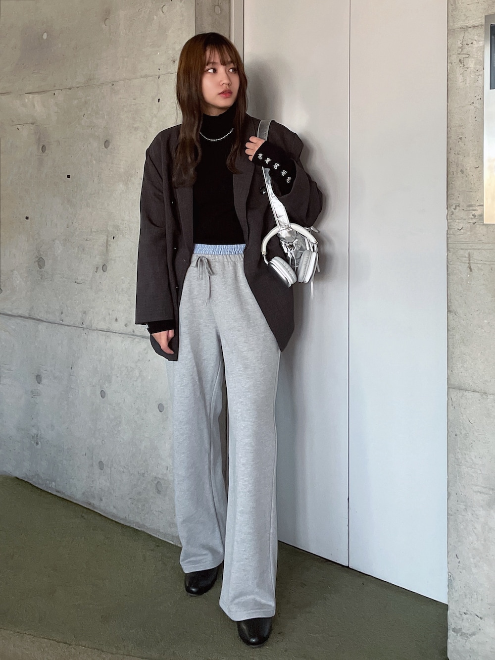 グレー系のスウェットパンツ、ブラック系のニット/セーター、グレー系のテーラードジャケットを着用したレディースの冬コーディネートの2枚目の写真