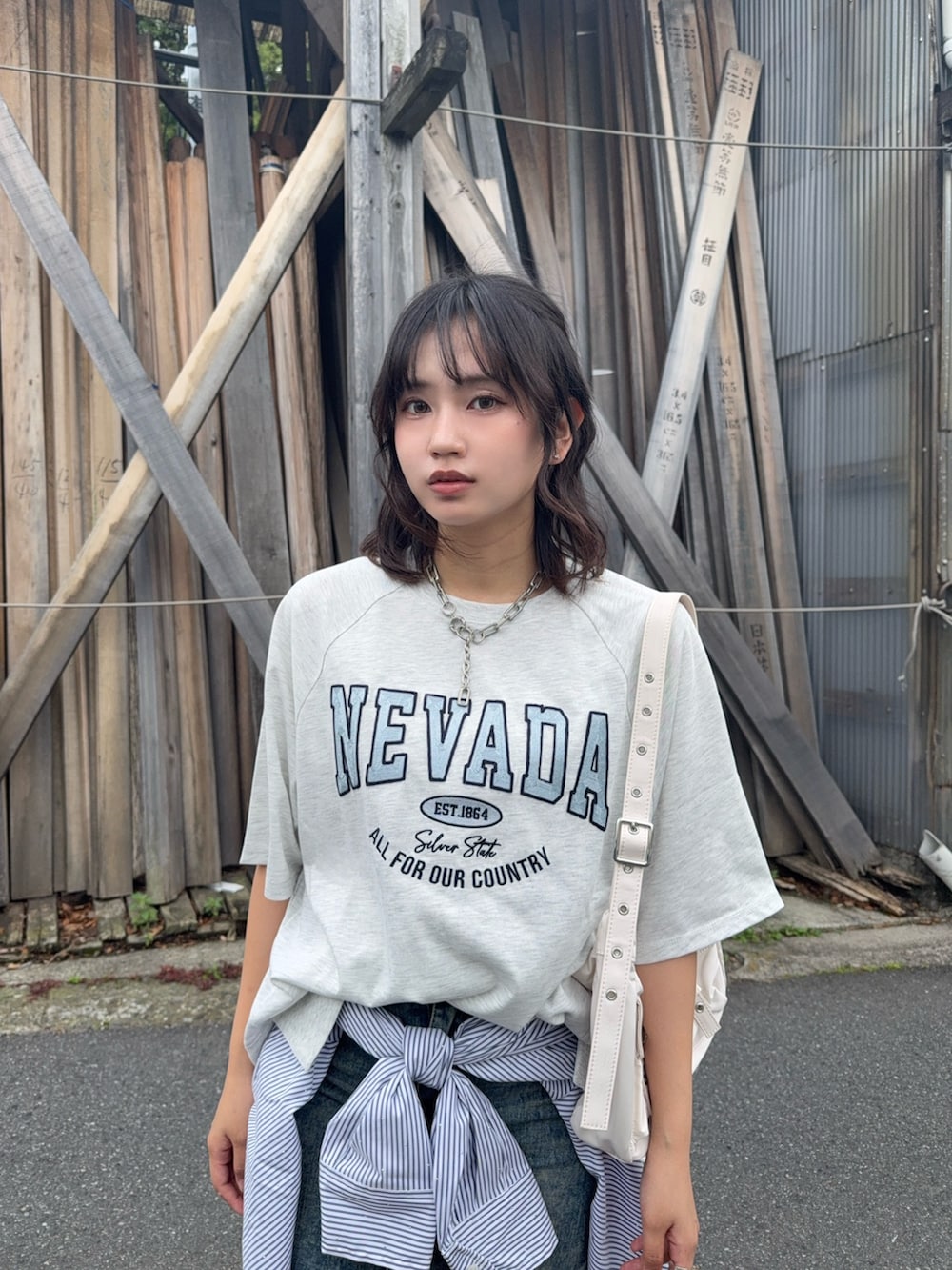 ベージュ系のTシャツ/カットソー、ブルー系のデニムスカート、ブラック系のローファーを着用したレディースの夏コーディネートの2枚目の写真