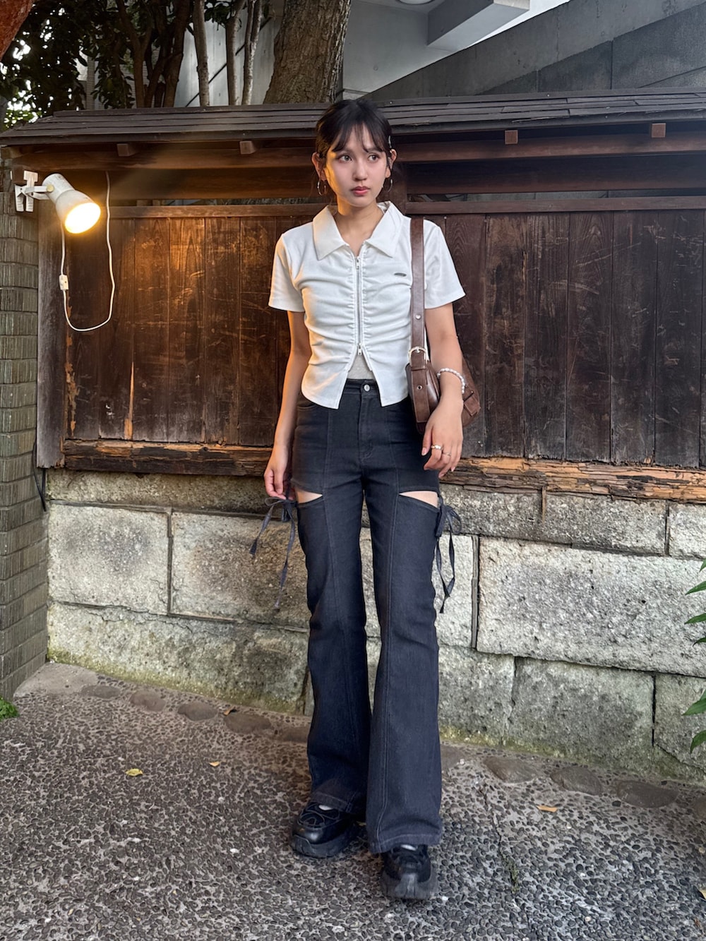 ブラック系のデニムパンツ、ホワイト系のTシャツ/カットソー、ブラック系のサンダルを着用したレディースの夏コーディネートの2枚目の写真