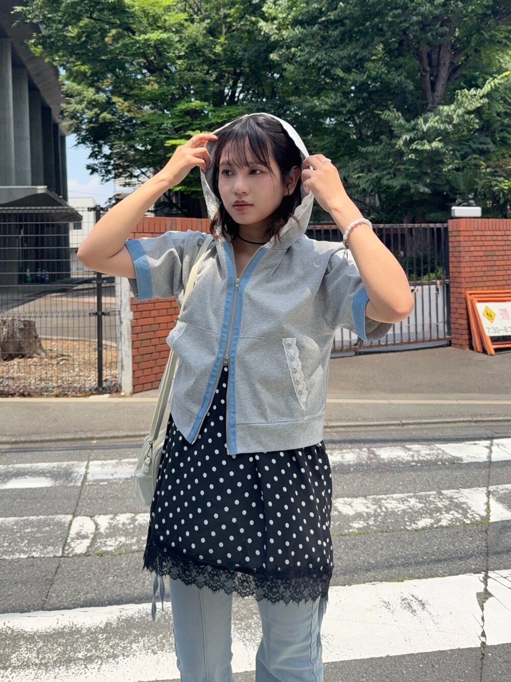 グレー系のパーカー、ブルー系のデニムパンツ、ブラック系のサンダルを着用したレディースの夏コーディネートの3枚目の写真