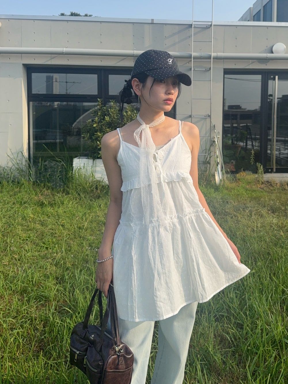 ホワイト系のチュニック、ブルー系のデニムパンツ、ブラック系のサンダルを着用したレディースの夏コーディネートの3枚目の写真