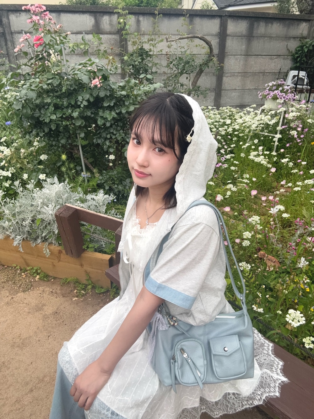 ホワイト系のチュニック、ベージュ系のパーカー、ブルー系のデニムパンツを着用したレディースの夏コーディネートの4枚目の写真