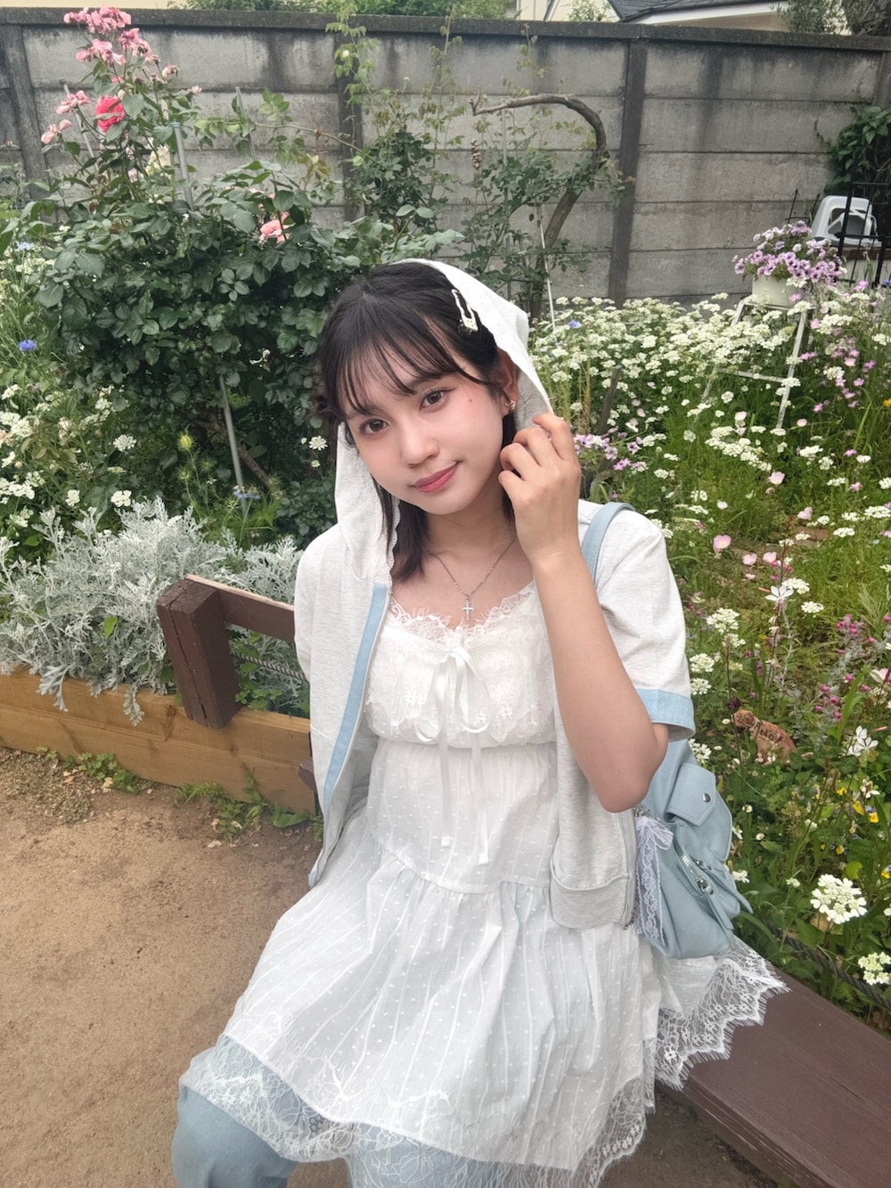 ホワイト系のチュニック、ベージュ系のパーカー、ブルー系のデニムパンツを着用したレディースの夏コーディネートの3枚目の写真