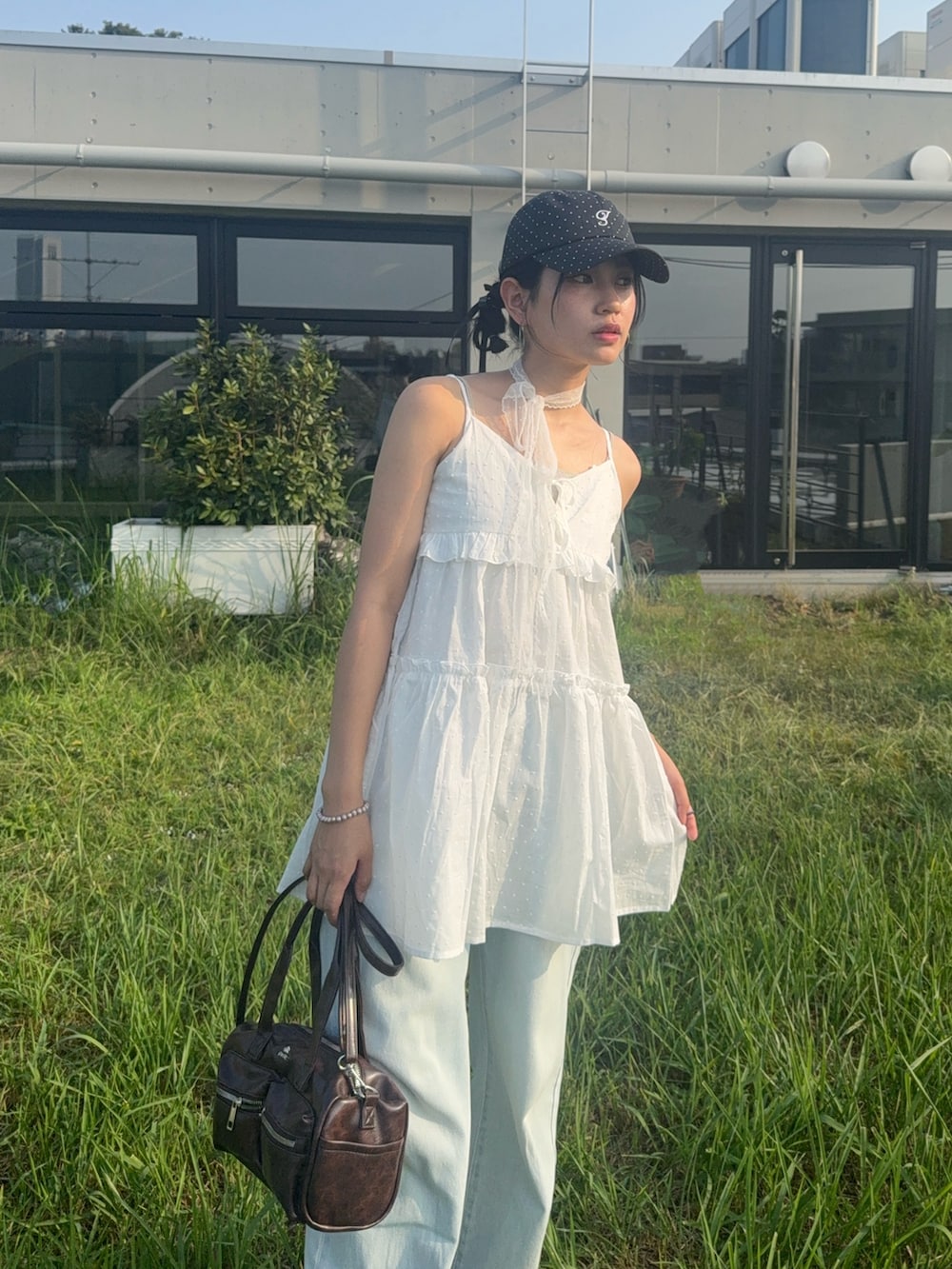 ホワイト系のチュニック、ブルー系のデニムパンツ、ブラック系のサンダルを着用したレディースの夏コーディネートの4枚目の写真