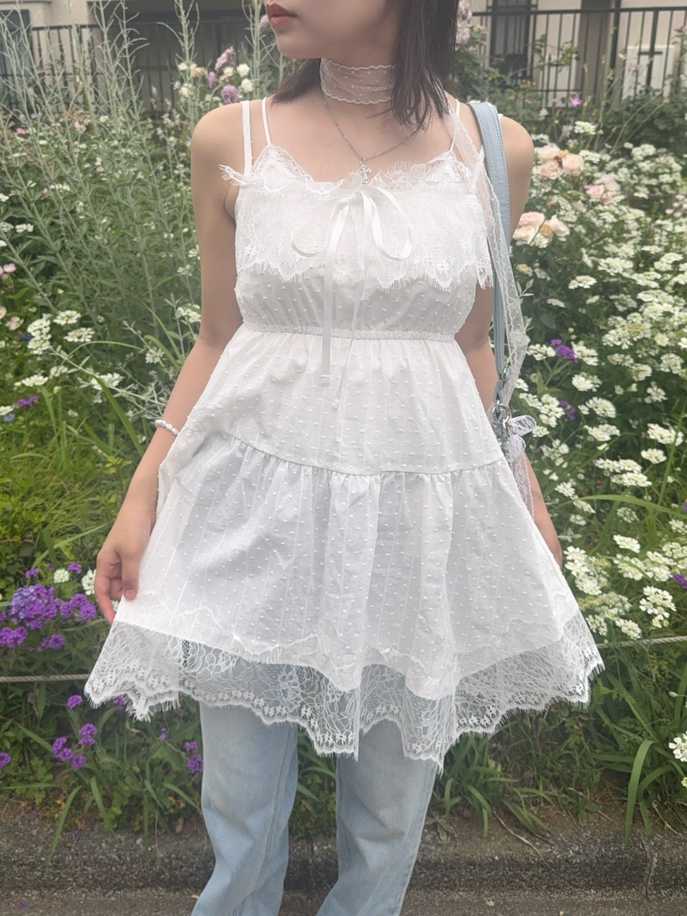ホワイト系のチュニック、ブルー系のデニムパンツを着用したレディースの夏コーディネートの2枚目の写真