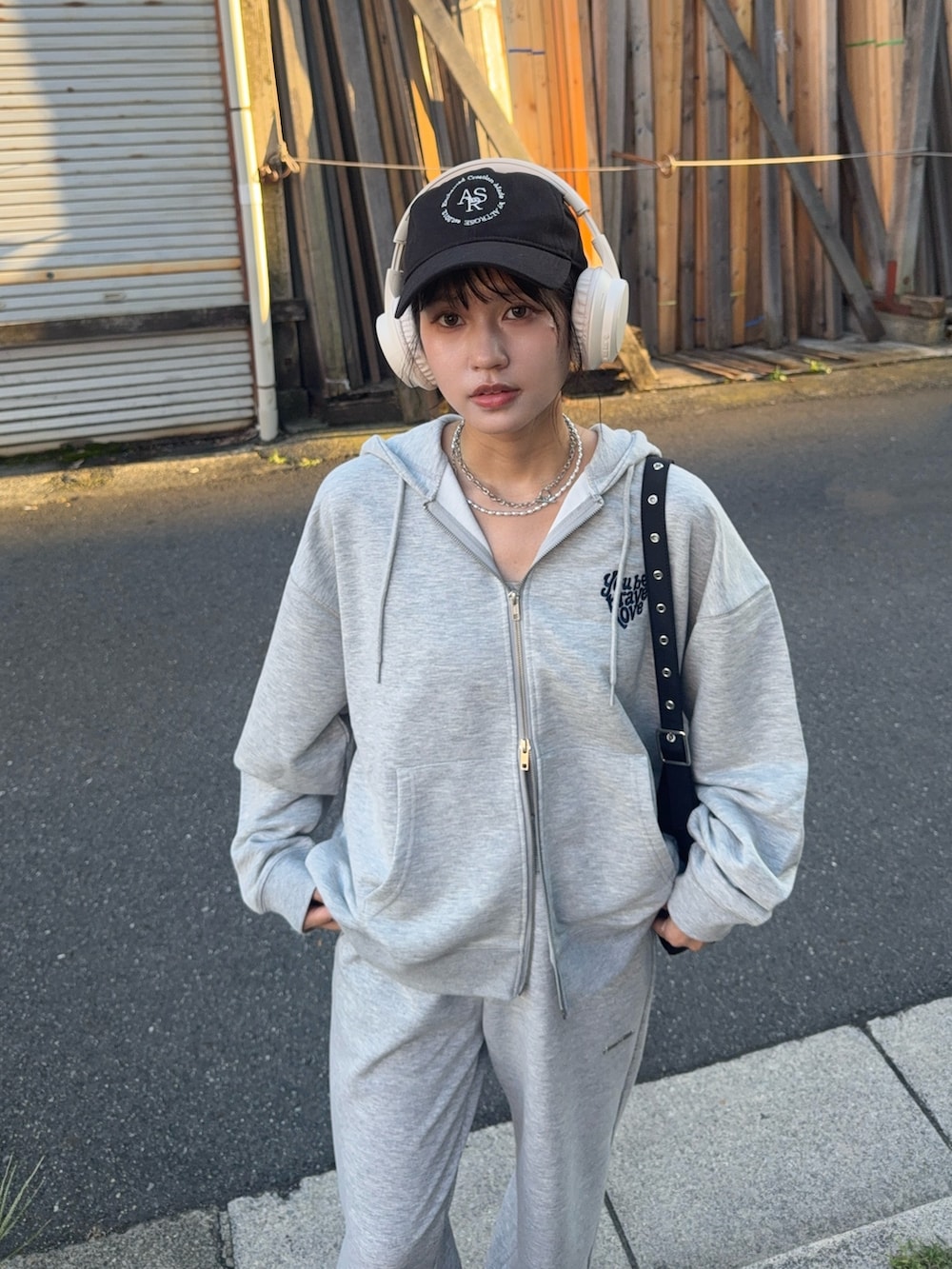 グレー系のパーカー、グレー系のスウェットパンツ、ブラック系のローファーを着用したレディースの夏コーディネートの3枚目の写真
