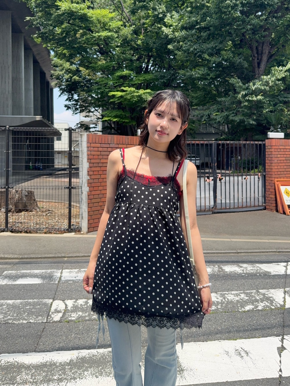 ブラック系のチュニック、ブルー系のデニムパンツ、レッド系のキャミソールを着用したレディースの夏コーディネートの3枚目の写真
