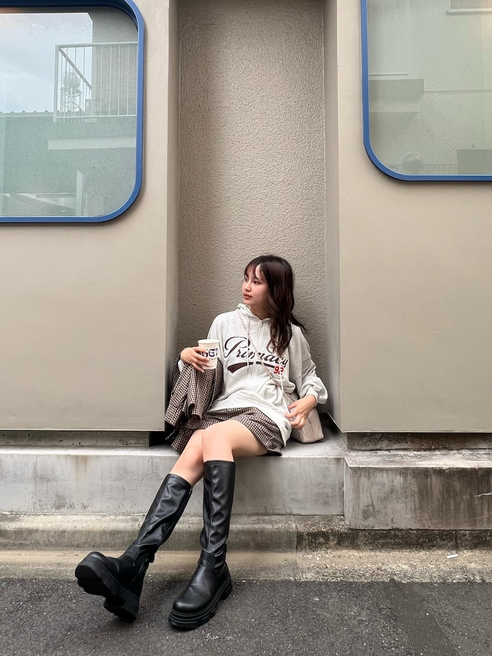 ベージュ系のパーカー、ホワイト系のショルダーバッグ、ブラック系のブーツを着用したレディースの秋コーディネートの2枚目の写真