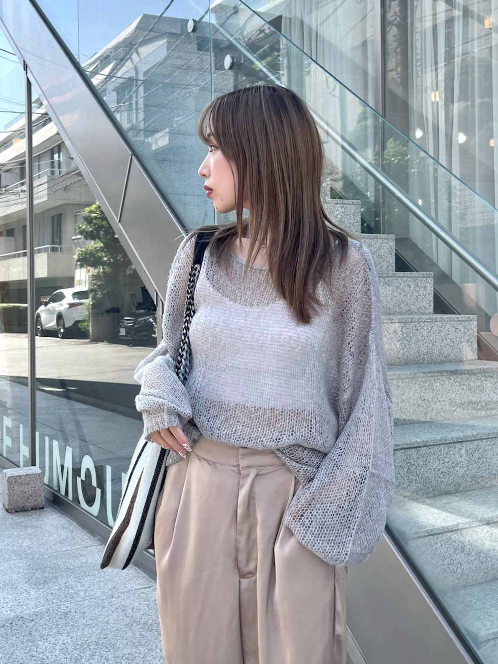 グレー系のニット/セーター、ベージュ系のスラックス、ベージュ系のサンダルを着用したレディースの秋コーディネートの2枚目の写真