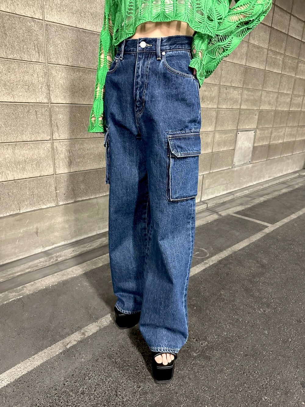 グリーン系のニット/セーター、ブルー系のデニムパンツを着用したレディースの春コーディネートの3枚目の写真