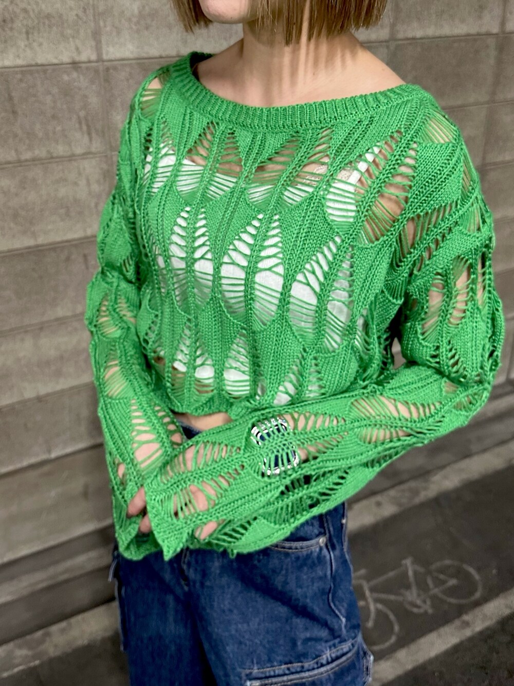 グリーン系のニット/セーター、ブルー系のデニムパンツを着用したレディースの春コーディネートの2枚目の写真