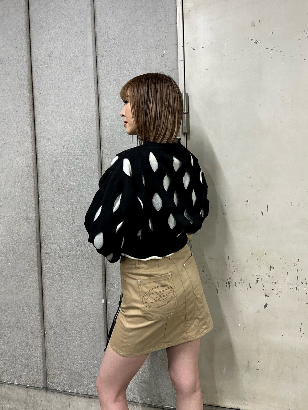 ブラック系のニット/セーター、ベージュ系のスカート、ブラック系のブーツを着用したレディースの冬コーディネートの2枚目の写真