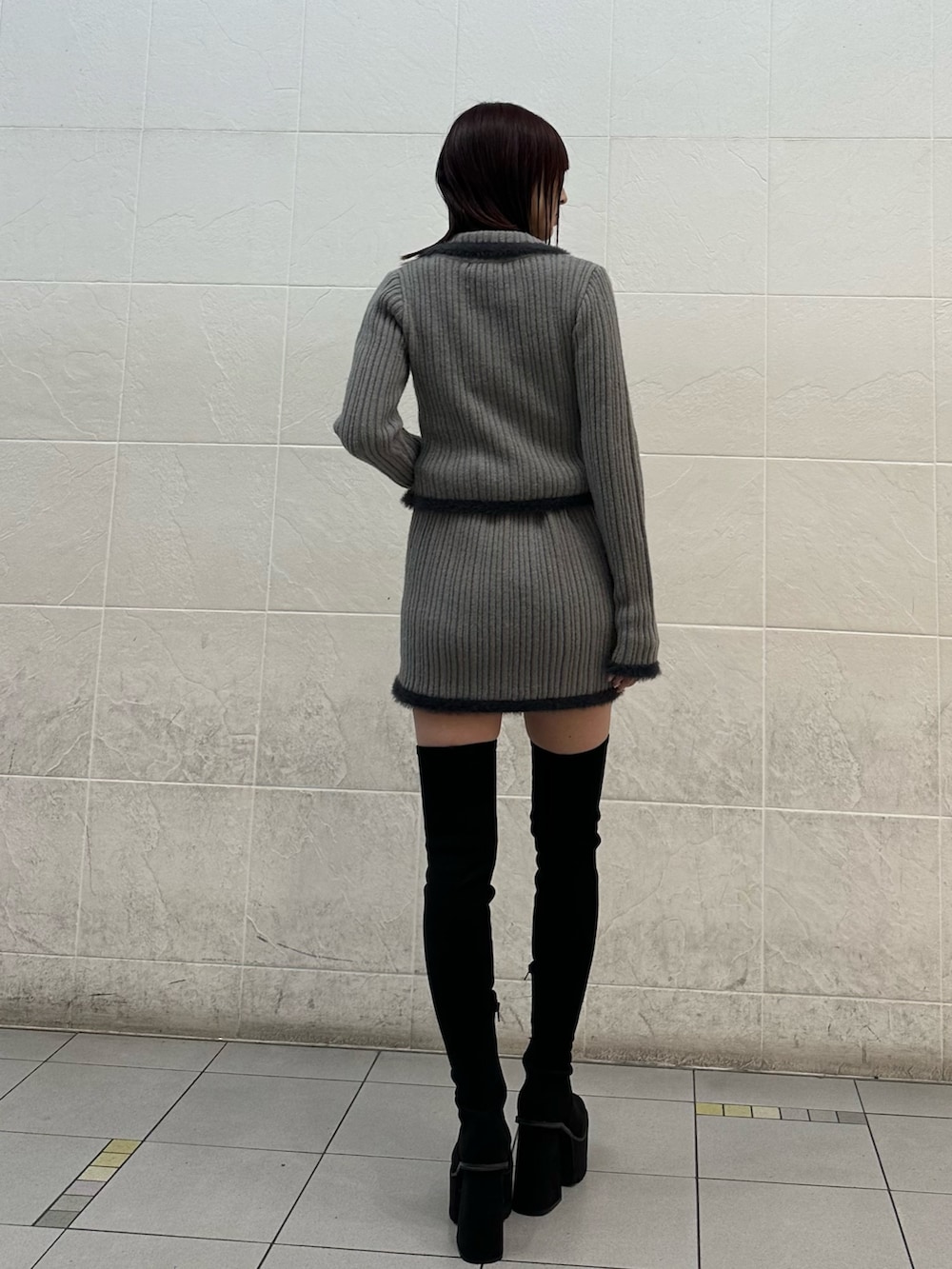 グレー系のニット/セーター、グレー系のスカート、ブラック系のブーツを着用したレディースの秋コーディネートの3枚目の写真