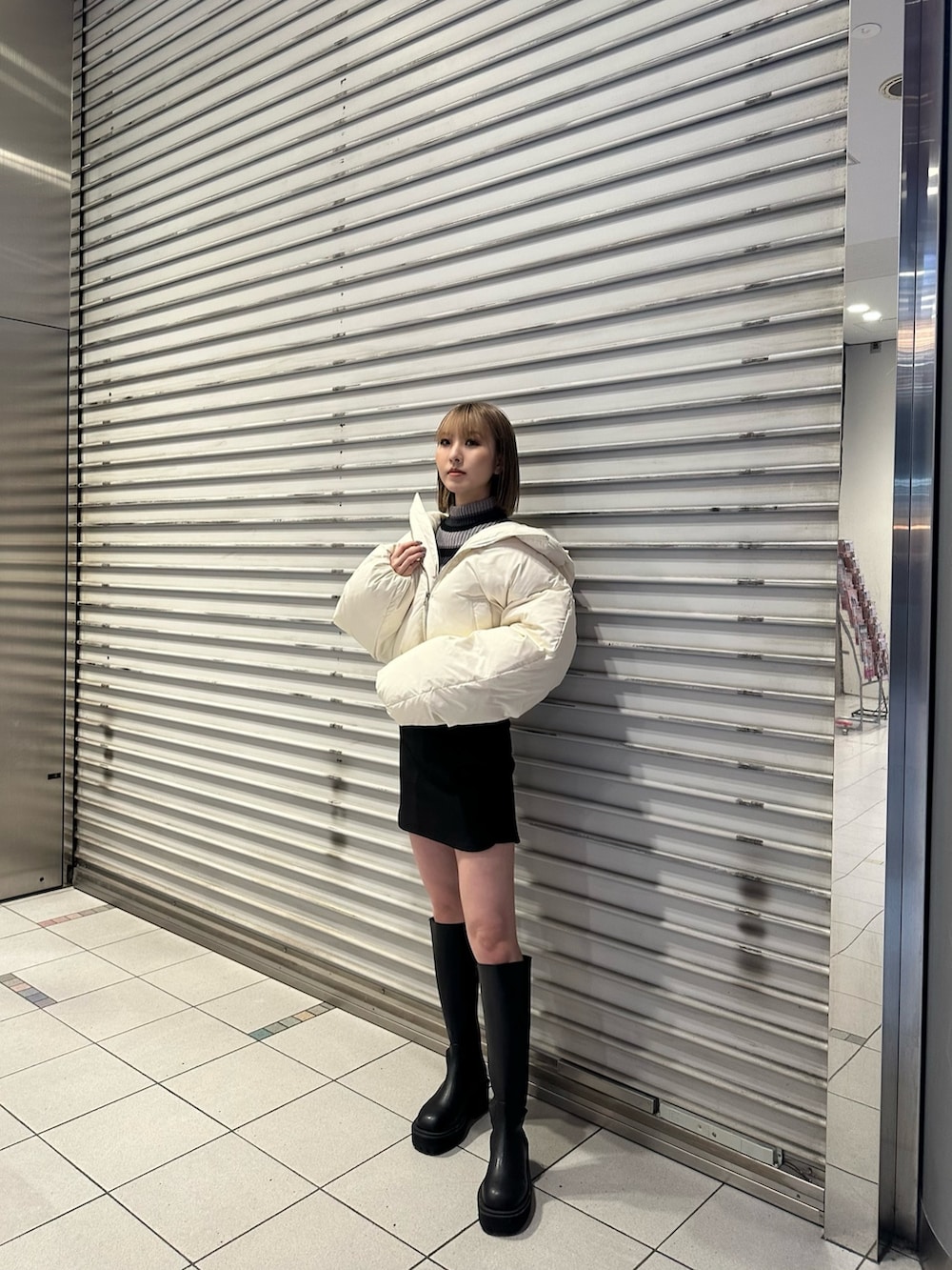 ホワイト系のダウンジャケット/コート、ブラック系のブーツを着用したレディースの冬コーディネートの2枚目の写真