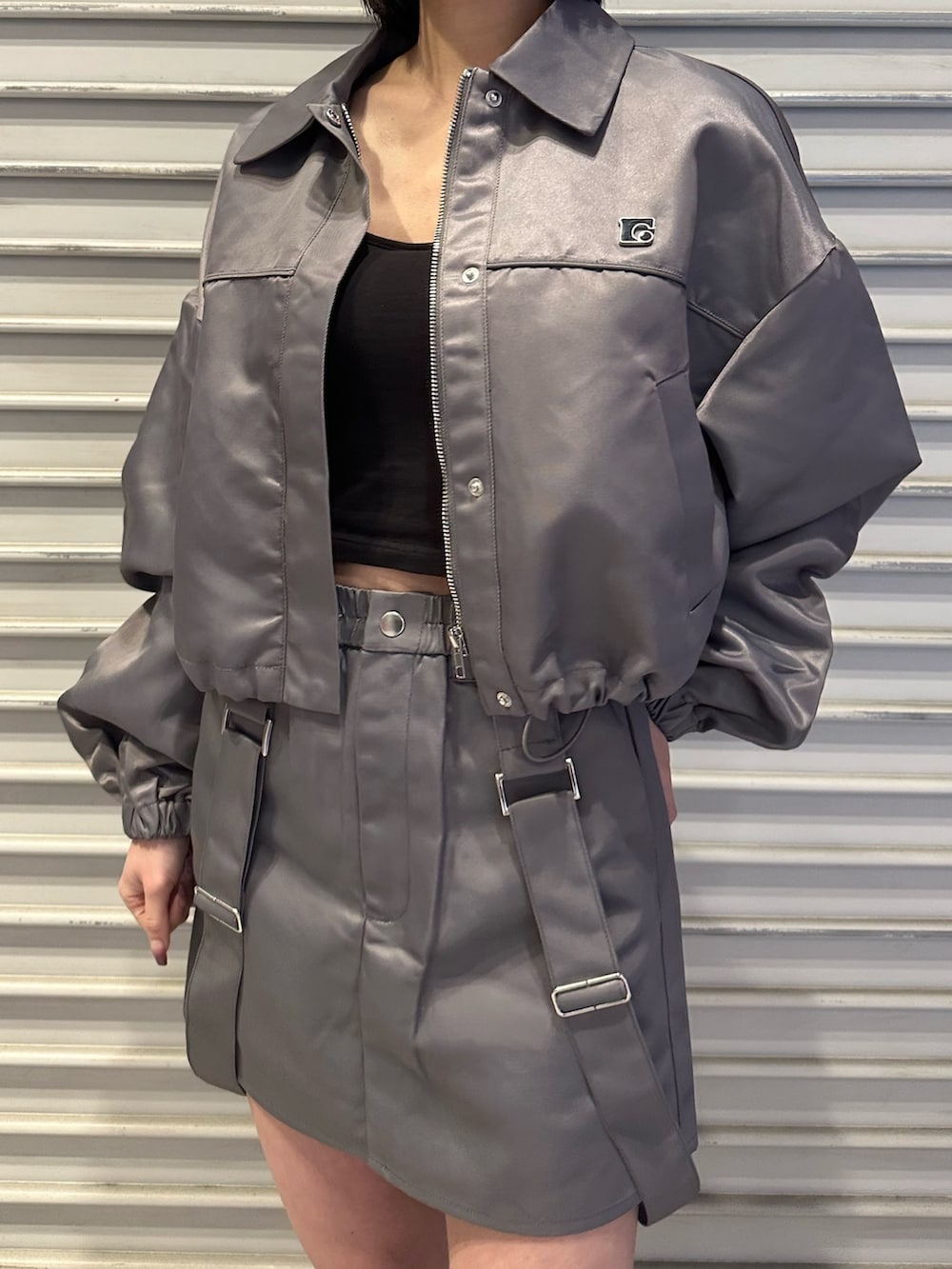 グレー系のブルゾン、グレー系のスカート、ブラック系のブーツを着用したレディースの冬コーディネートの2枚目の写真