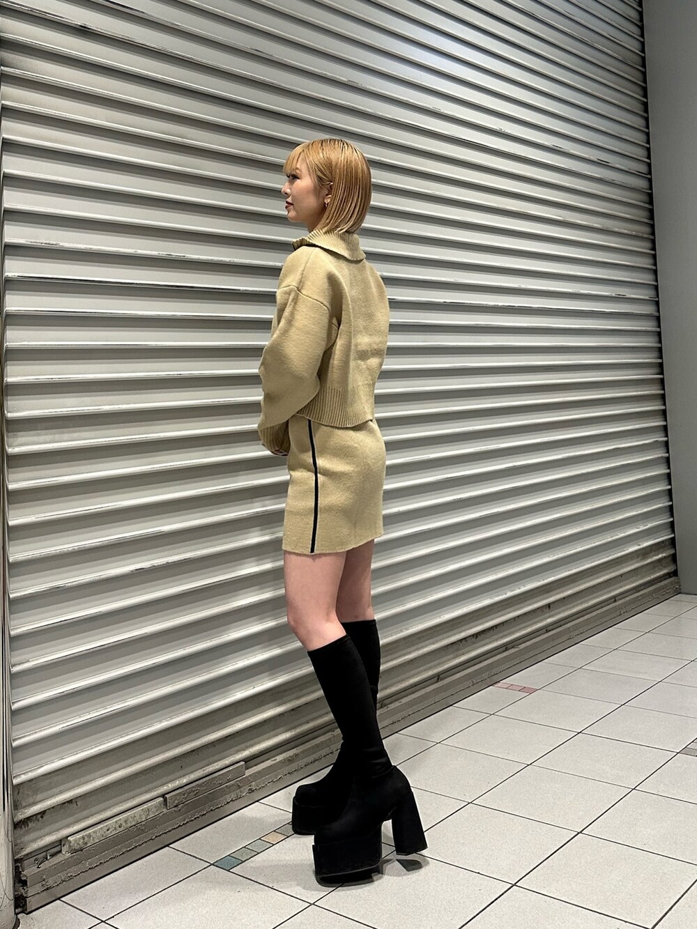 ベージュ系のニット/セーター、ベージュ系のスカート、その他のブーツを着用したレディースの秋コーディネートの3枚目の写真