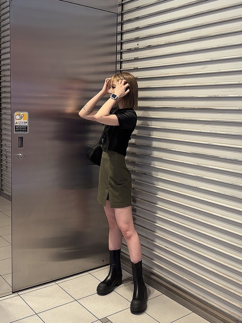 ブラック系のTシャツ/カットソー、グリーン系のスカート、ブラック系のブーツを着用したレディースの夏コーディネートの2枚目の写真