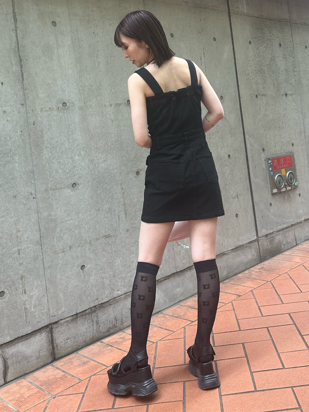 ブラック系のワンピース、ブラック系のサンダル、ピンク系のショルダーバッグを着用したレディースの春コーディネートの3枚目の写真